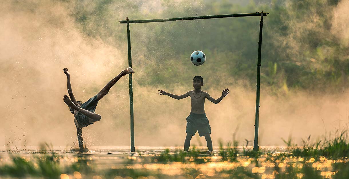 ragazzi che giocano a calcio in un campo improvvisato